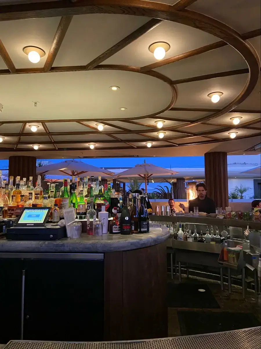 Location: Calabra, Santa Monica, California, Wood Highlights: Warm wood trim at face of oval shaped bar island and ceiling