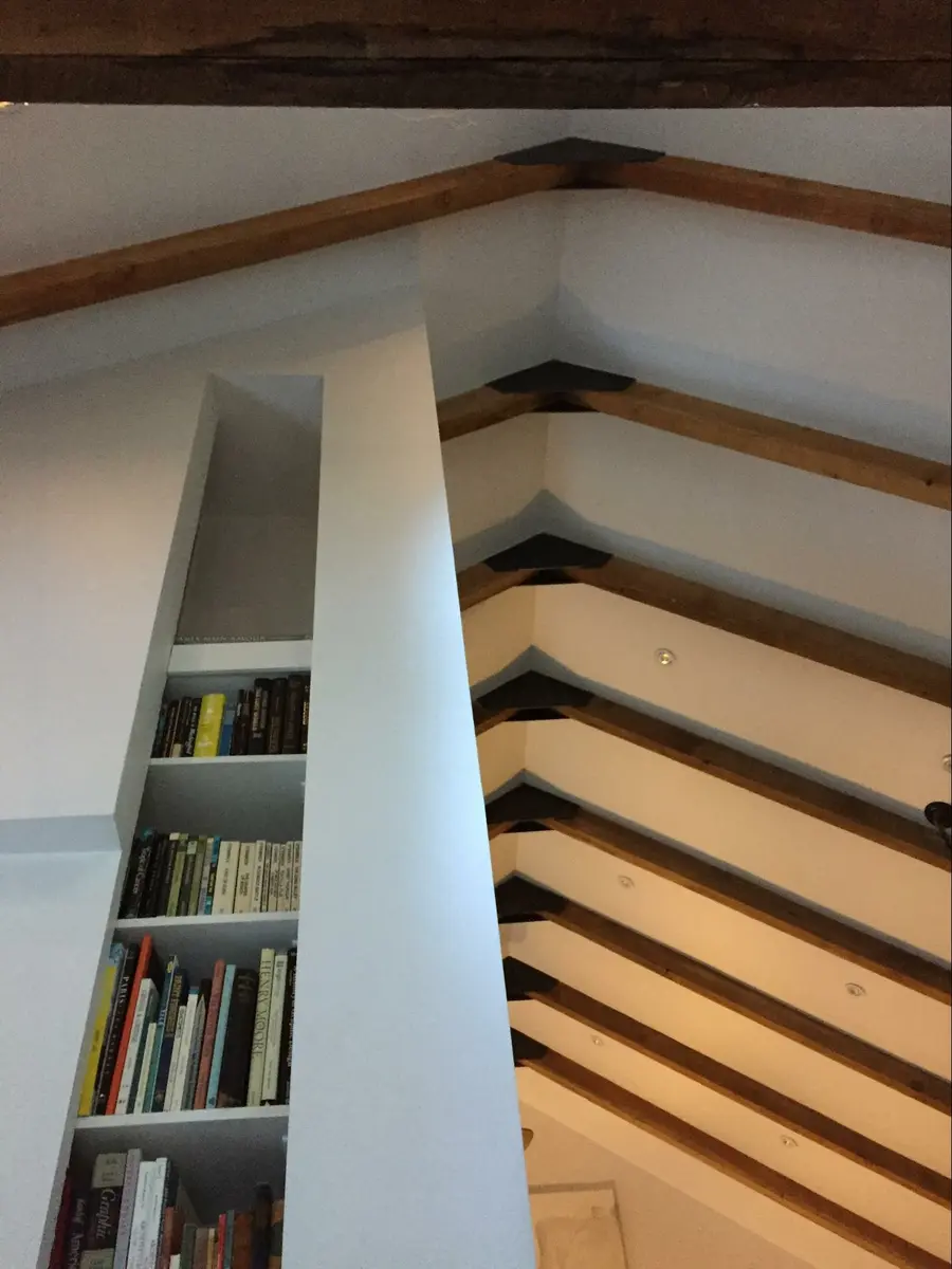 Private residence, Marin County, California, Wood Highlights: Custom-built S4S shelving integrated into a vertical slot library with coveted books in a great room with wood beams and metal gussets