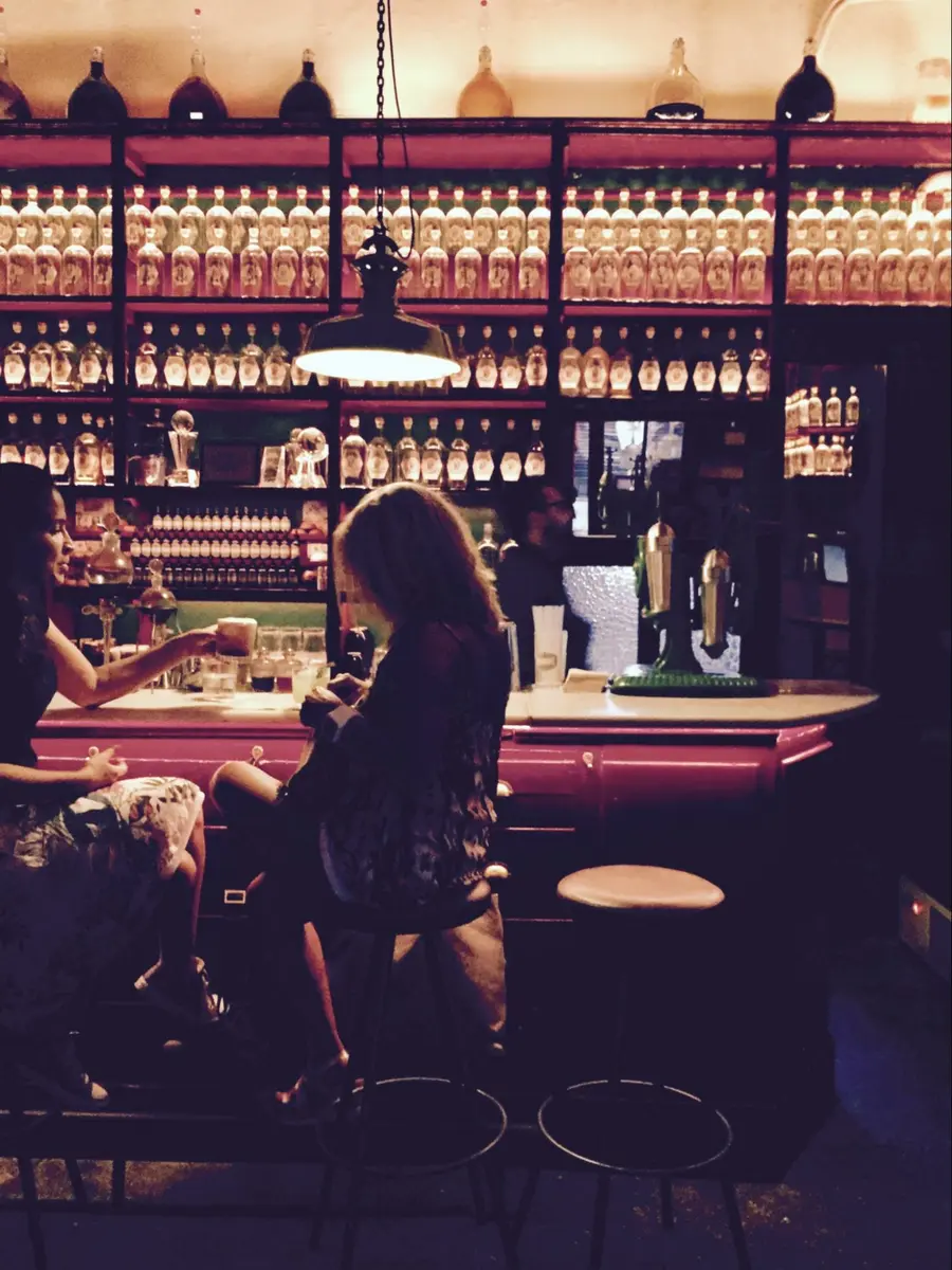 Location: Dr. Stravinsky, El Born, Barcelona, Spain, Wood Highlights: Red painted wood trim at bar and painted wood S4S shelving at bar back, wood trim at bar counter