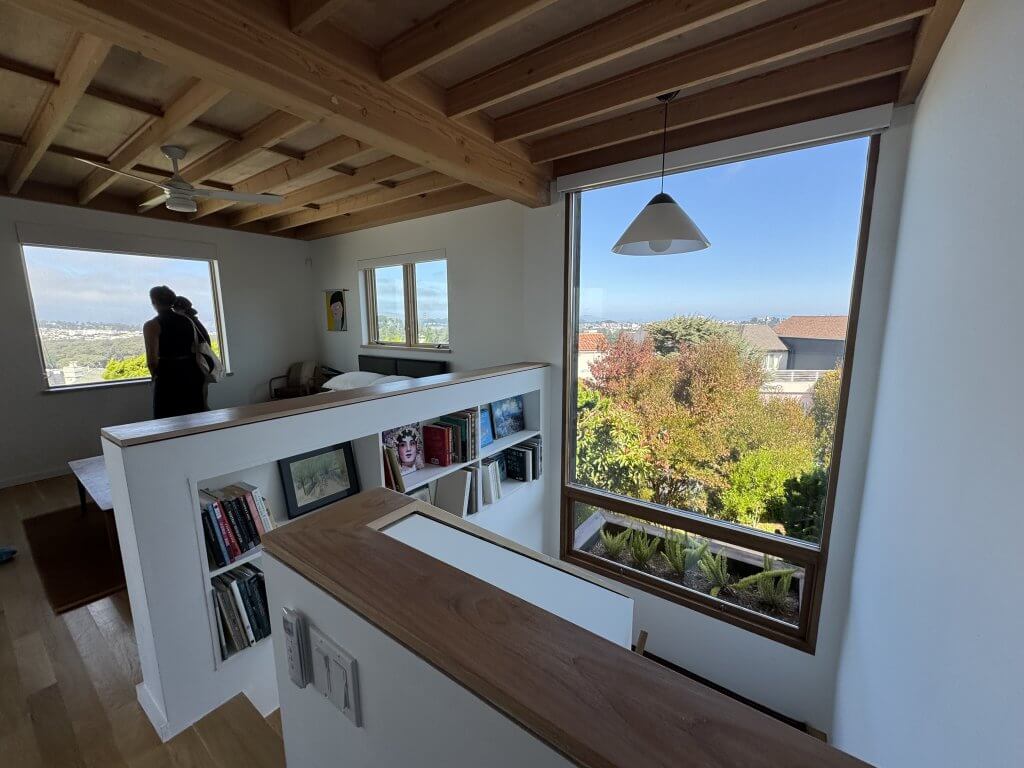 Wood HIghlights: Light natural wood flooring, stairs, wall caps, and window trim inside this ADU in Golden Gate Heights, echo the ceiling palette and elevate the space, designed by AIASF architects Felix Associates.