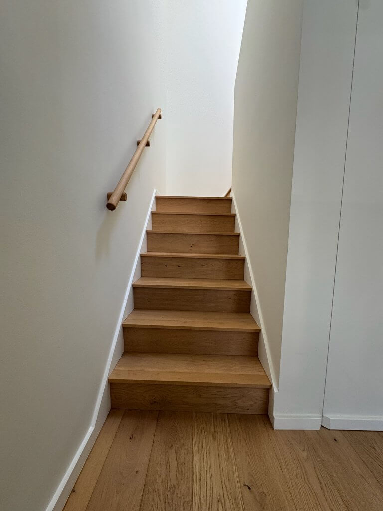 Location: Hayes Valley House, San Francisco, California, Wood Highlights: wide plank white oak floors, modern painted baseboards, natural wood stair railing matching stair treads and risers create a minimalist and serene aesthetic