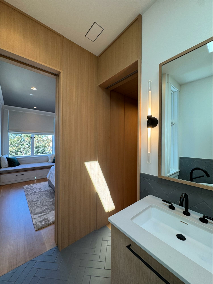 Wood Highlights: The primary bath is decked out with more natural wood trim at door casings and full height panels which intersect with tiled white walls and offer more warmth while leading gently to the primary walk in closet, high end detailing that has impact on the quality of the space and therefore the everyday experience
