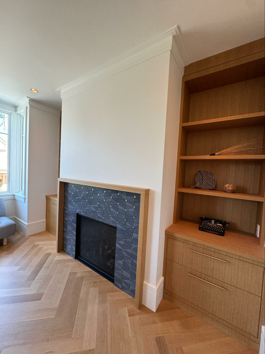 Location: Eureka Valley Home, San Francisco, California, Wood Highlights: A closer look at the tall baseboards with a crisp reveal, shows a true design anchor while the stepped, built up, modern crown moulding works in concert and continues to wrap the rooms ceiling, dying into the cabinetry and fireplace mantel design in contrasting complementary finishes. The herringbone pattern created by the wood T&G flooring is at a larger scale, bridging traditional designs with modern flair.