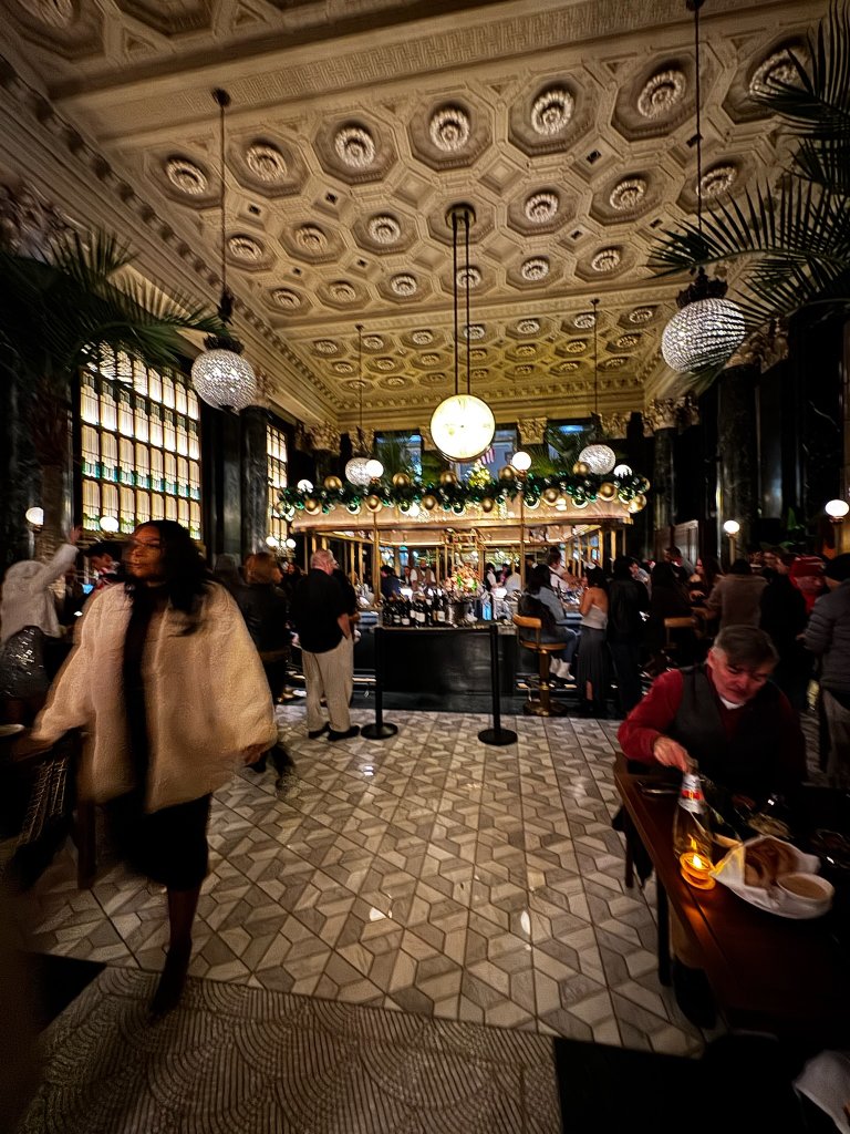 Location: Bourbon Steak, San Francisco, California, Wood Highlights: The central bar design features multiple moulding profiles below the countertop, anchoring the room. Edge details at the planters flanking the booths smartly mark the entry.