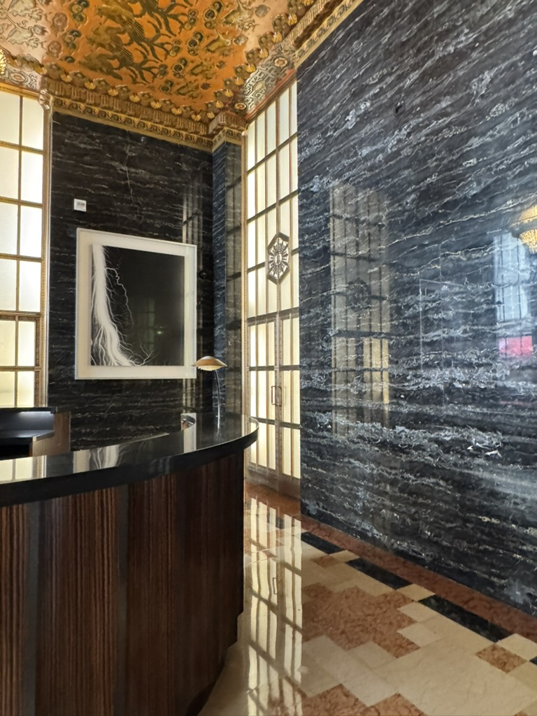 Location: San Francisco, California, Wood Highlights: The stunning reception desk grand design with large scale moulding made of natural wood provides a contrast with the glossy polished marble and metal finishes around.