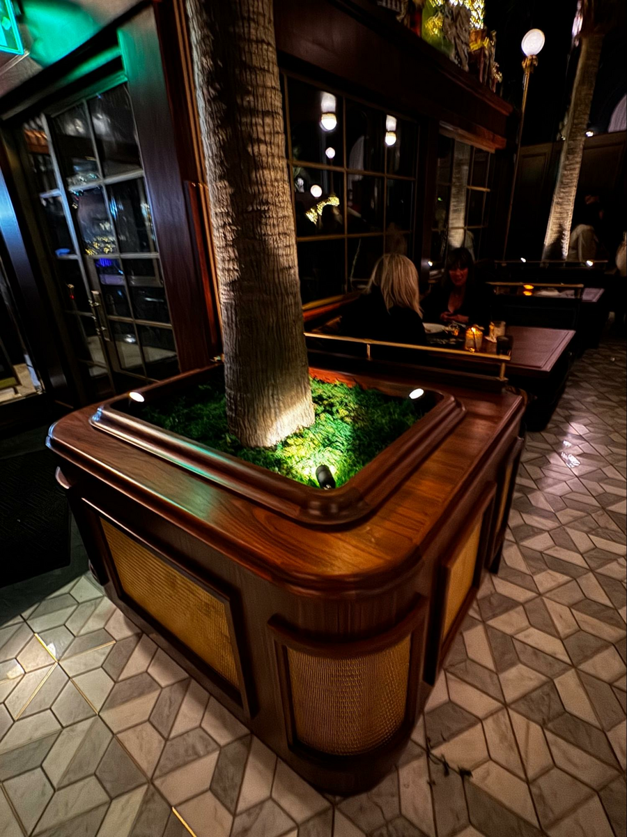 Location: Bourbon Steak, San Francisco, California, Wood Highlights: The central bar design features multiple moulding profiles below the countertop, anchoring the room. Edge details at the planters flanking the booths smartly mark the entry.